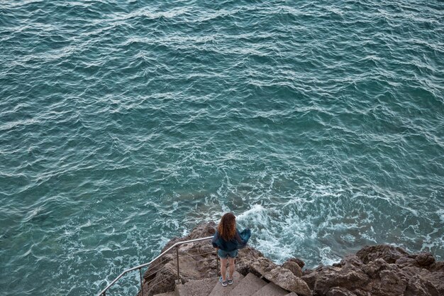 Vista de ángulo alto de una mujer de pie en las escaleras junto al mar