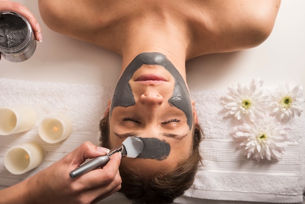 Vista de ángulo alto de una mujer que recibe máscara facial en el salón de belleza