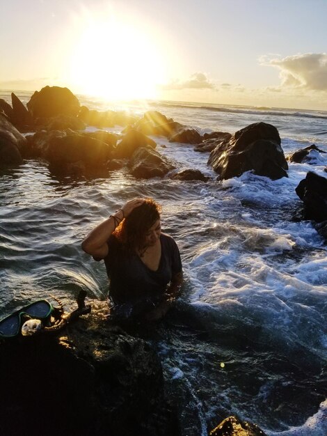 Foto vista de ángulo alto de una mujer sentada en el mar durante la puesta de sol