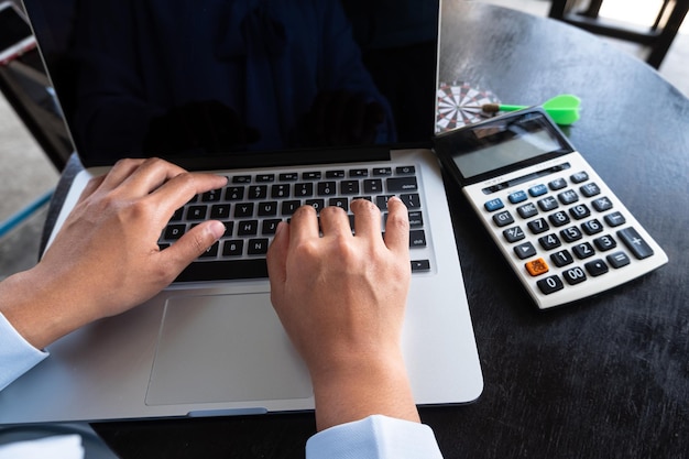 Vista de ángulo alto de una mujer trabajando con una calculadora y un dardo en la mesa