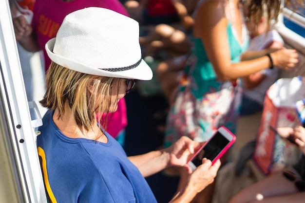 Foto vista de ángulo alto de una mujer usando el teléfono móvil mientras está sentada en un barco