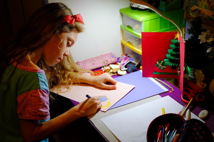 Foto vista de ángulo alto de una niña dibujando en papel de cartón en la mesa