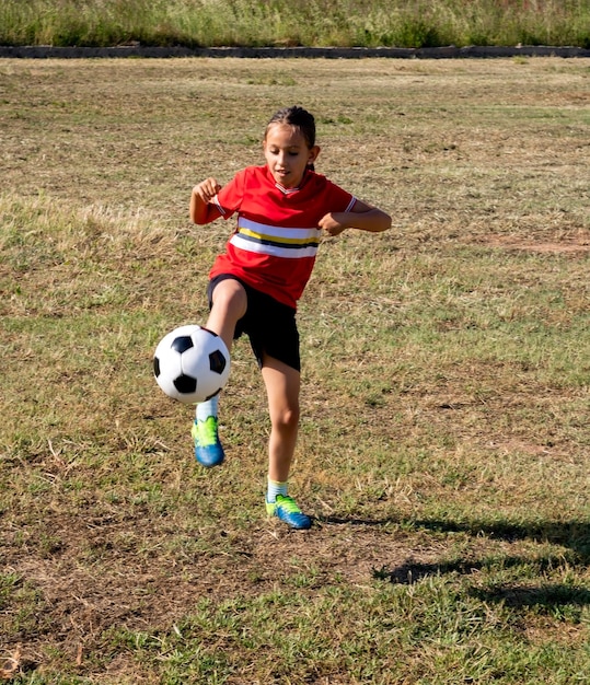 Foto vista de ángulo alto de una niña jugando al fútbol en tierra