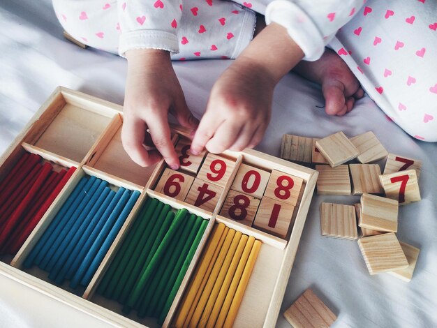 Foto vista de ángulo alto del niño arreglando bloques con número en la caja en la cama