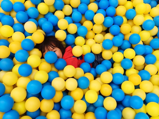 Vista de ángulo alto de un niño cubierto de bolas de colores