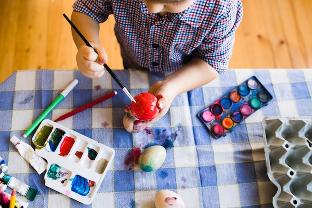 Vista de ángulo alto de un niño pintando huevos en la mesa