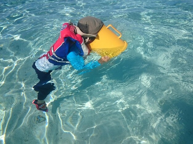 Foto vista de ángulo alto de un niño con un recipiente en la piscina