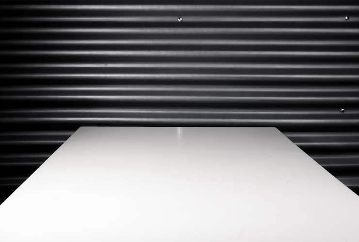 Foto vista de ángulo alto de pared negra metálica y mesa de madera blanca