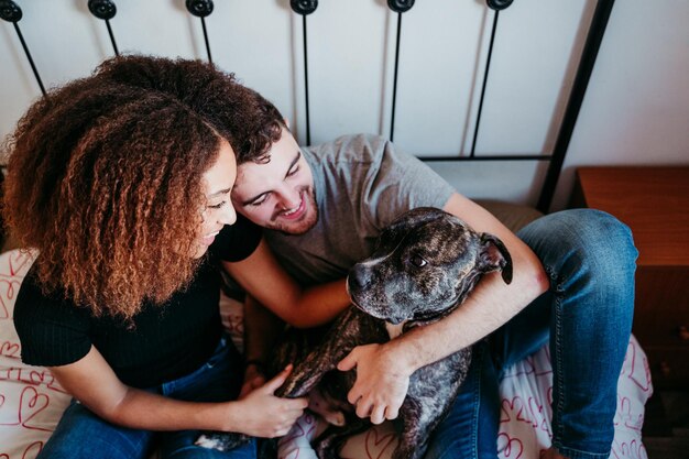 Foto vista de ángulo alto de una pareja con un perro relajándose en la cama en casa