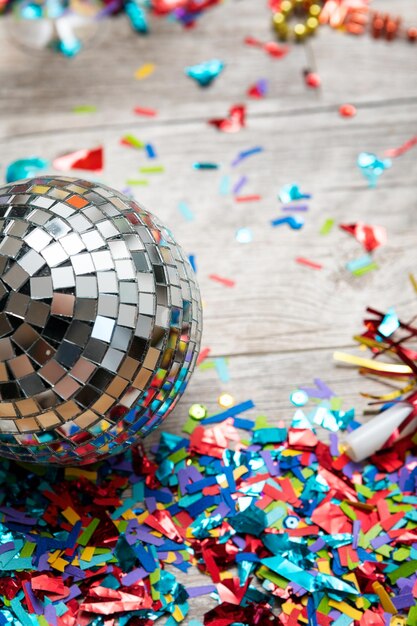 Vista de ángulo alto de una pelota de discoteca por confeti colorido en una mesa de madera
