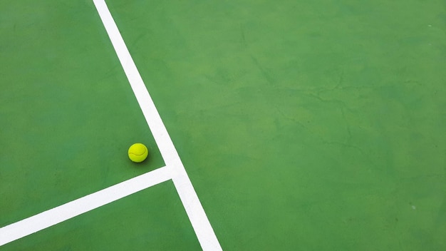 Foto vista de ángulo alto de la pelota de tenis amarilla en la cancha de tenis verde