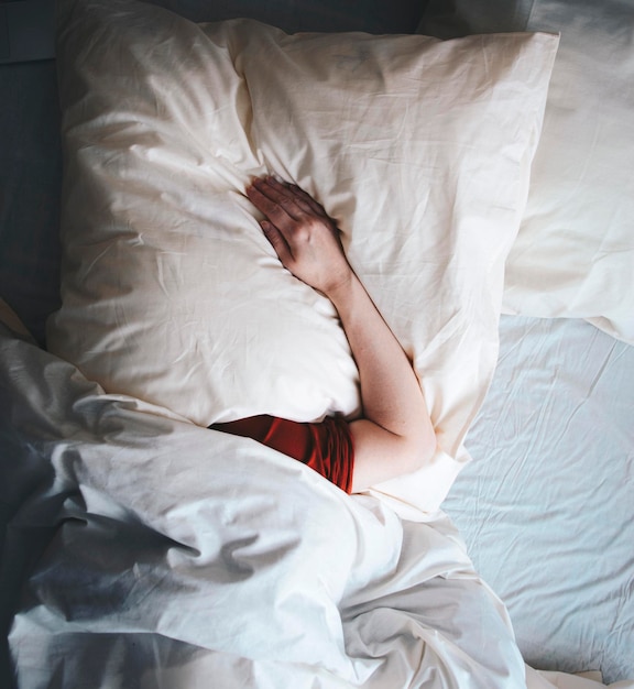 Vista de ángulo alto de una persona durmiendo en la cama en casa
