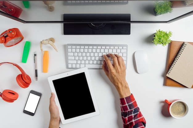 Vista de ángulo alto de una persona usando una computadora portátil y una tableta digital en la mesa.