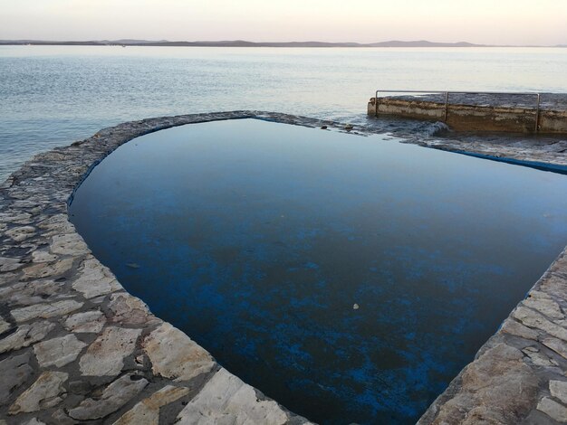 Vista en ángulo alto de la piscina por el mar contra el cielo