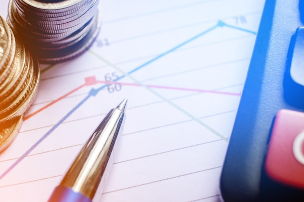 Vista de ángulo alto de la pluma con monedas y calculadora en papel
