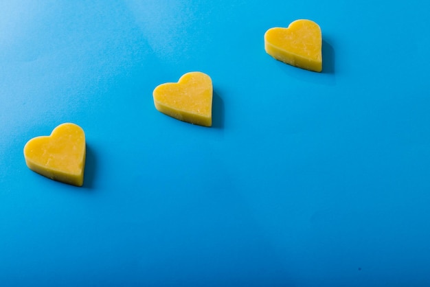Vista de ángulo alto de queso amarillo en forma de corazón dispuesto sobre fondo azul, espacio de copia
