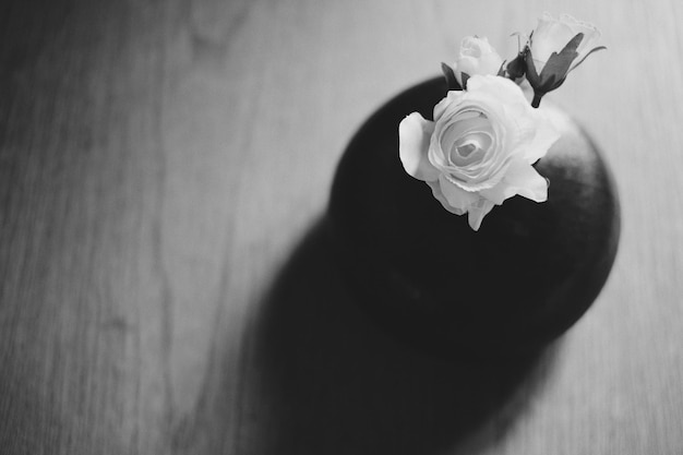 Foto vista de ángulo alto de rosas en jarrón en una mesa de madera