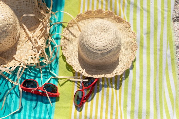 Vista de ángulo alto de sombreros para el sol y gafas de sol en la toalla en la playa durante el día soleado