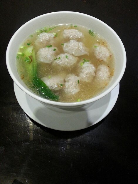 Vista de ángulo alto de la sopa de wonton servida en un cuenco en la mesa