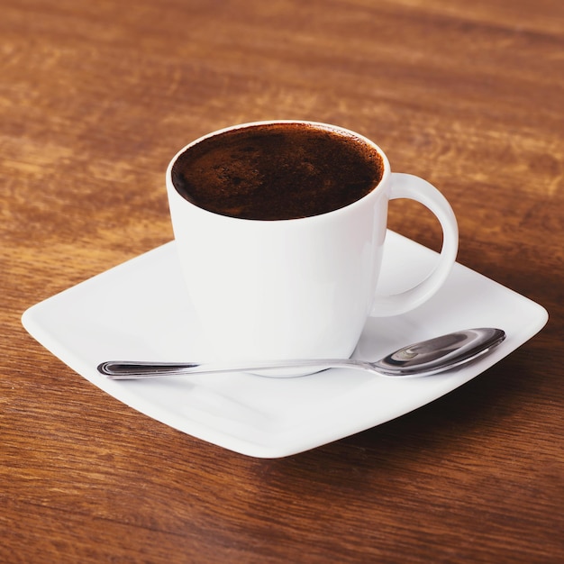 Foto vista de ángulo alto de una taza de café en un platillo con una cuchara en la mesa