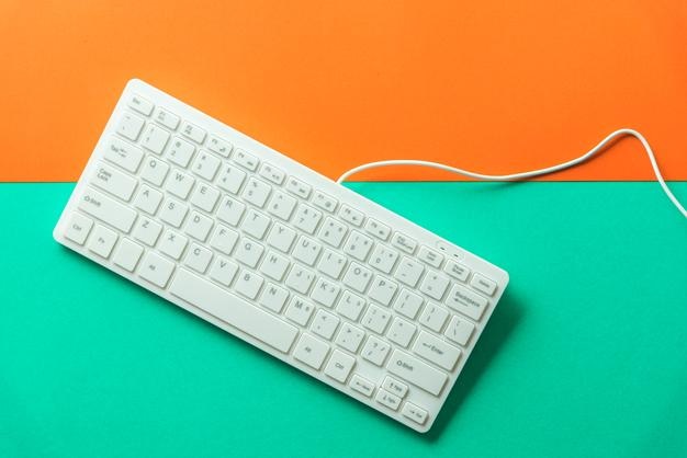 Vista de ángulo alto del teclado de la computadora sobre un fondo de color
