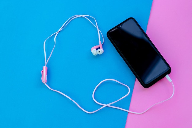 Foto vista de ángulo alto de teléfono inteligente con auriculares en el oído en papel