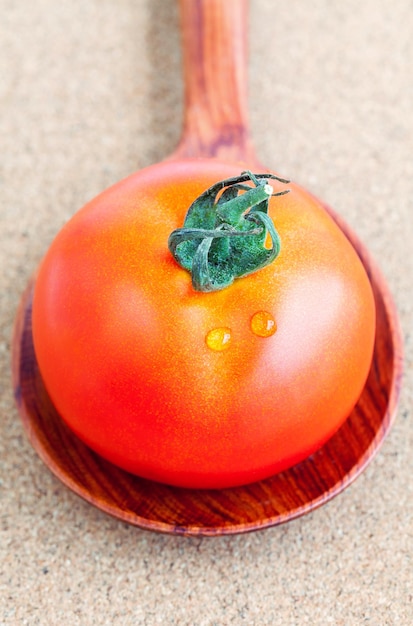 Foto vista de ángulo alto del tomate en una cuchara de madera en la mesa