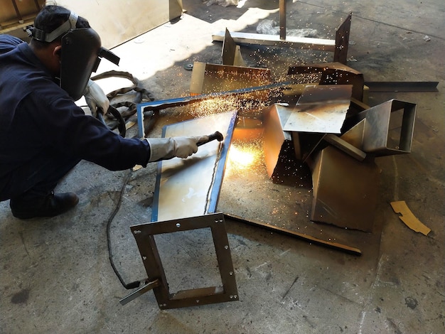 Foto vista en ángulo alto de un trabajador soldando metal en el taller