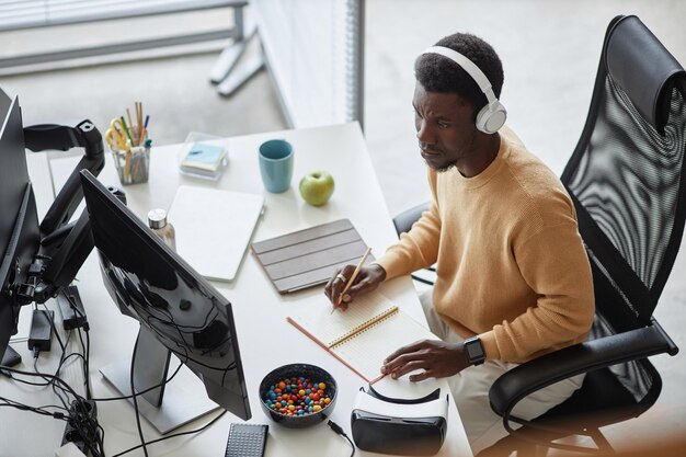Vista de ángulo alto del trabajo de planificación del programador afroamericano en su lugar de trabajo