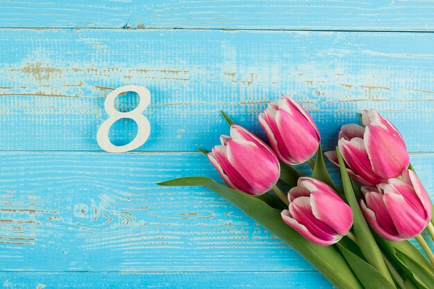 Foto vista de ángulo alto de tulipanes rosados en la mesa junto a la piscina