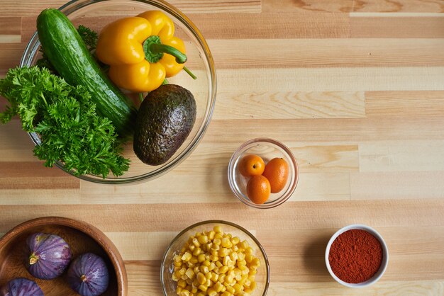 Vista de ángulo alto de vegetales frescos en un tazón para ensalada y otros ingredientes en la mesa