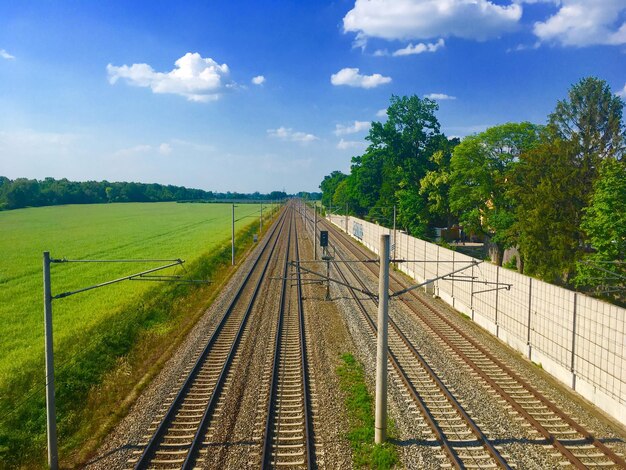 Foto vista de ángulo alto de las vías del ferrocarril por los árboles contra el cielo azul