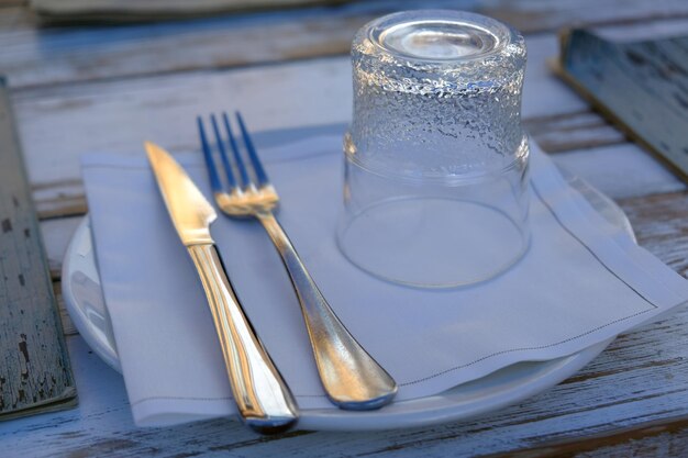 Vista de ángulo alto de vidrio y cubiertos con servilleta en el plato sobre la mesa