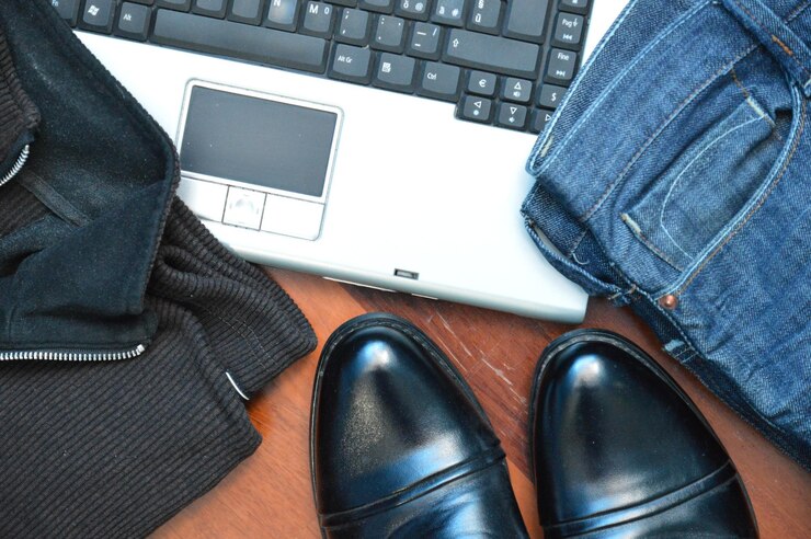 Foto vista de ángulo alto de zapatos con ropa por computadora portátil en la mesa