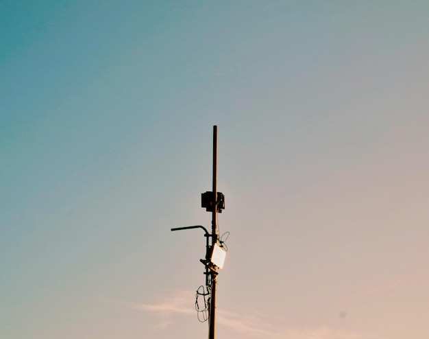 Foto vista de ángulo bajo de la antena en el poste contra el cielo durante la puesta del sol