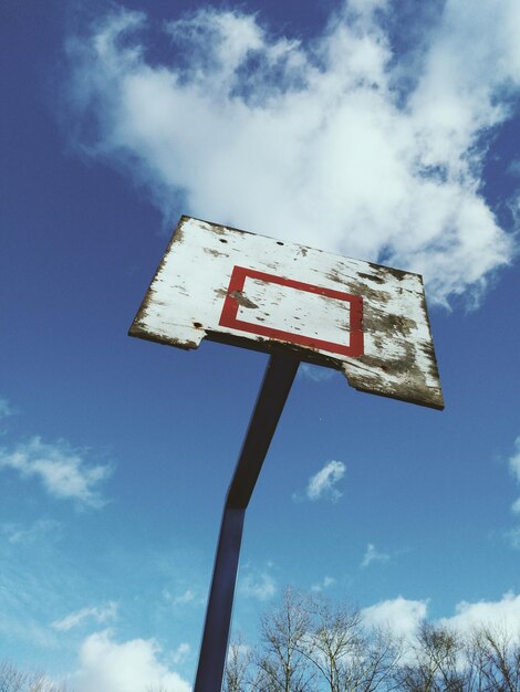 Vista de ángulo bajo de un aro de baloncesto abandonado contra el cielo azul