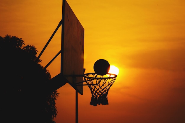Vista de ángulo bajo del aro de baloncesto contra el cielo naranja