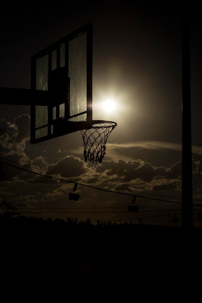 Foto vista de ángulo bajo del aro de baloncesto contra el cielo durante la puesta de sol
