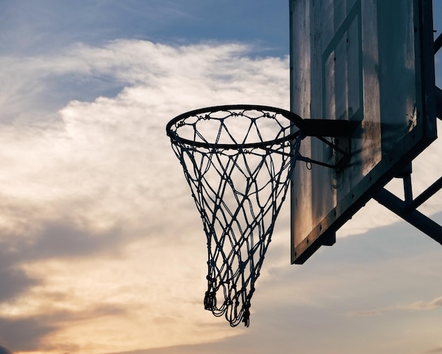 Vista de ángulo bajo del aro de baloncesto contra el cielo durante la puesta de sol