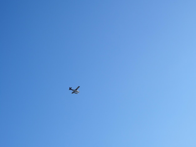 Vista de bajo ángulo de un avión volando en un cielo azul claro