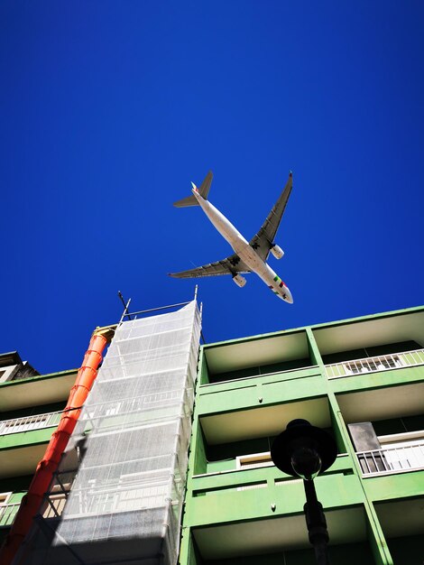 Foto vista de bajo ángulo de un avión volando contra un cielo azul claro