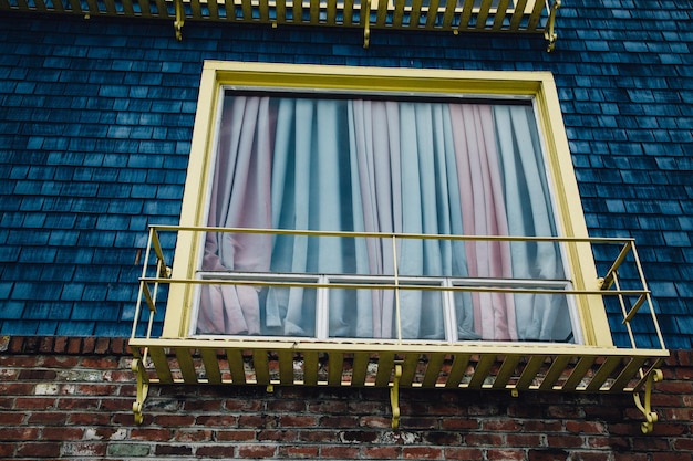 Foto vista de bajo ángulo del balcón metálico por una ventana con cortina