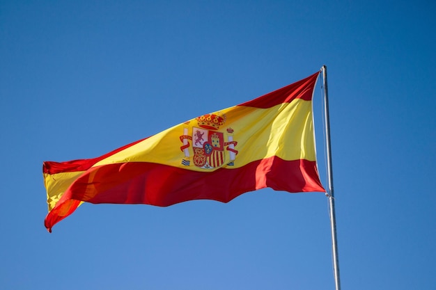 Vista en bajo ángulo de la bandera española contra el cielo azul