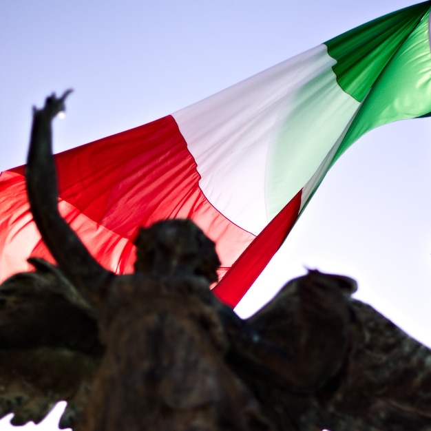 Vista en bajo ángulo de la bandera y la estatua contra el cielo