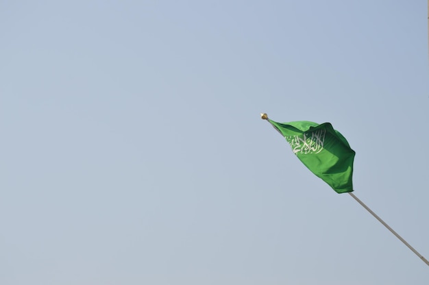 Foto vista de bajo ángulo de una bandera saudí volando contra un cielo despejado