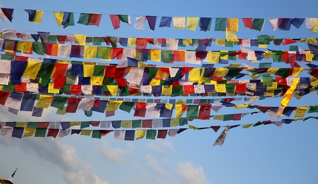 Foto vista de ángulo bajo de banderas de oración multicolores colgando contra el cielo azul