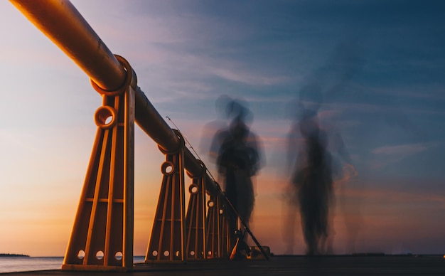 Vista de ángulo bajo de las barandillas en el muelle contra el cielo durante la puesta de sol