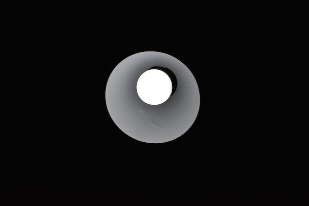 Vista en bajo ángulo de la bombilla iluminada contra un fondo negro