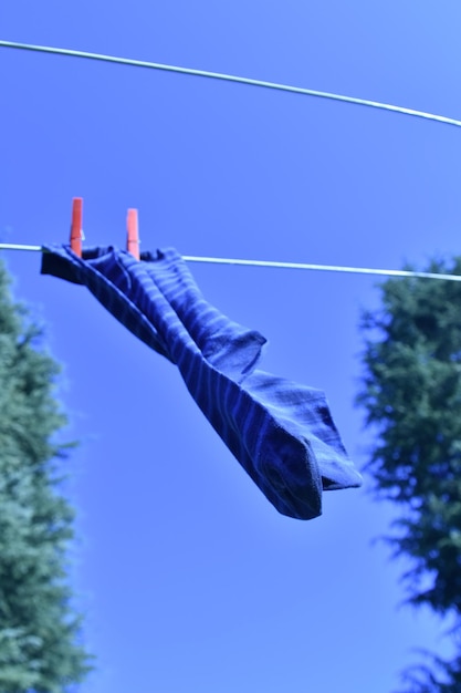 Foto vista de ángulo bajo de calcetines secándose en una cuerda contra un cielo despejado