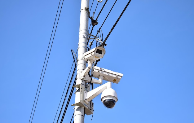 Vista de ángulo bajo de las cámaras de seguridad en el poste contra un cielo azul claro